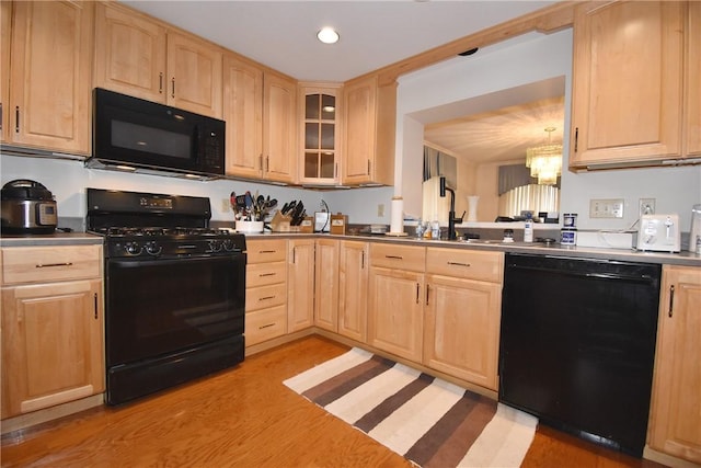 kitchen with glass insert cabinets, light wood-style floors, light brown cabinets, a sink, and black appliances