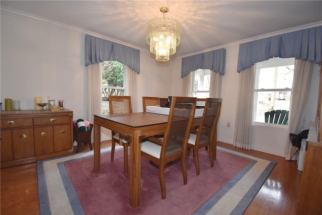 dining room with wood finished floors, crown molding, baseboards, and an inviting chandelier