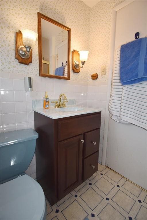 bathroom featuring wallpapered walls, tile patterned flooring, a wainscoted wall, and vanity