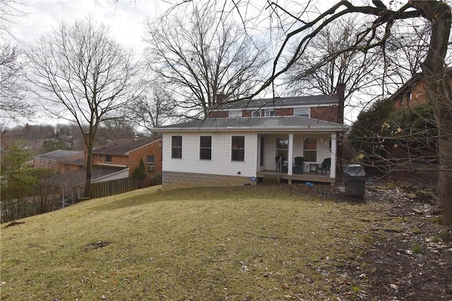 rear view of property featuring covered porch, a yard, and a chimney