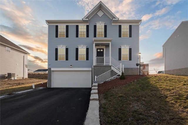 view of front facade featuring aphalt driveway, a front lawn, central AC unit, and an attached garage