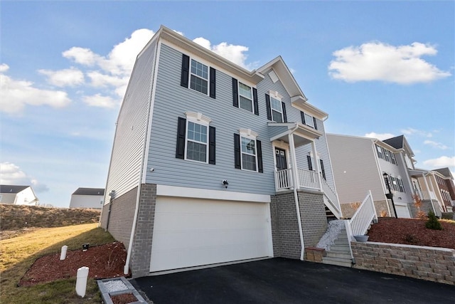 view of front of property with brick siding, stairway, an attached garage, and driveway