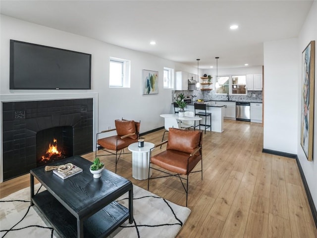 living area with light wood-type flooring, a fireplace, baseboards, and recessed lighting