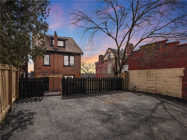 exterior space featuring fence private yard, a shingled roof, and brick siding