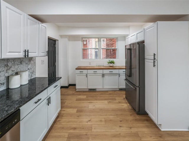 kitchen with appliances with stainless steel finishes, light wood-type flooring, white cabinets, and backsplash