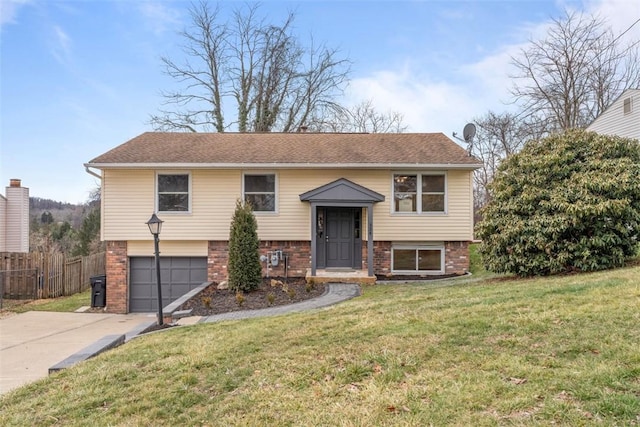 raised ranch featuring a garage, concrete driveway, fence, a front lawn, and brick siding