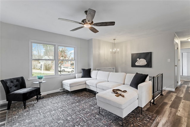 living room with ceiling fan with notable chandelier, dark wood finished floors, and baseboards