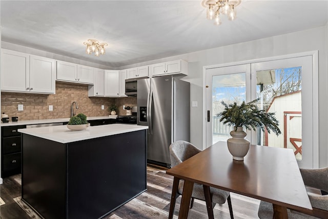 kitchen featuring light countertops, appliances with stainless steel finishes, a kitchen island, and wood finished floors