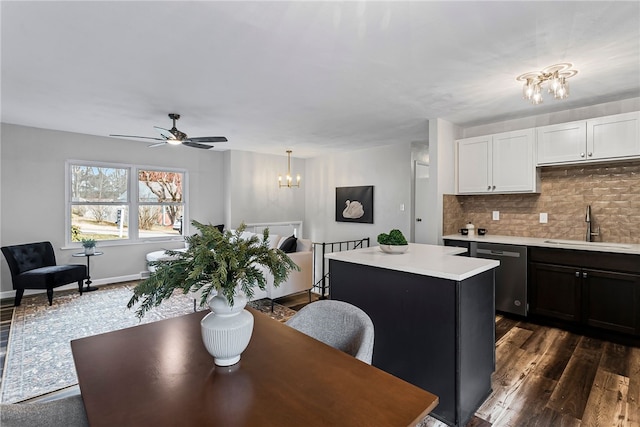 dining space with dark wood-style floors, ceiling fan with notable chandelier, and baseboards