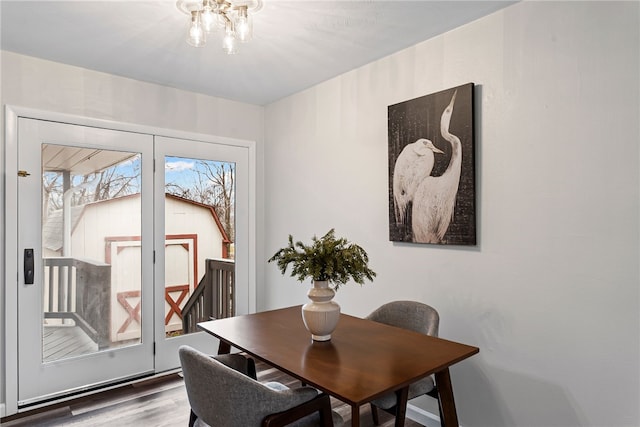 dining space with wood finished floors and an inviting chandelier