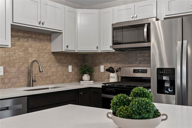 kitchen with stainless steel appliances, light countertops, a sink, and tasteful backsplash