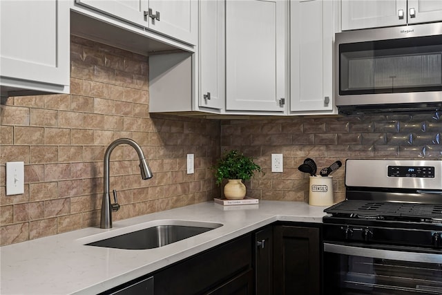 kitchen featuring stainless steel appliances, white cabinets, a sink, and tasteful backsplash