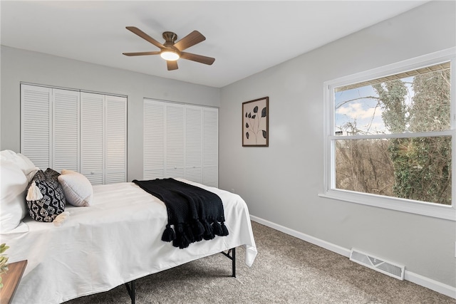 bedroom featuring ceiling fan, carpet flooring, visible vents, baseboards, and multiple closets