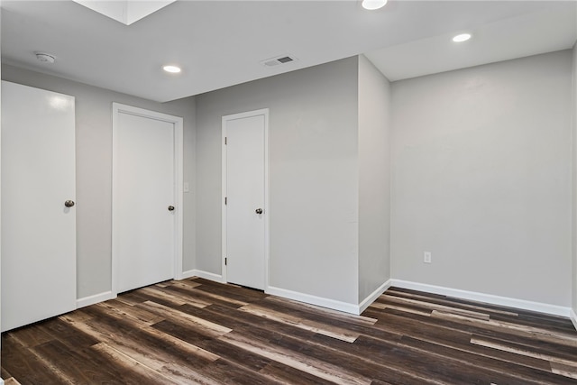 unfurnished room featuring dark wood-style floors, visible vents, baseboards, and recessed lighting