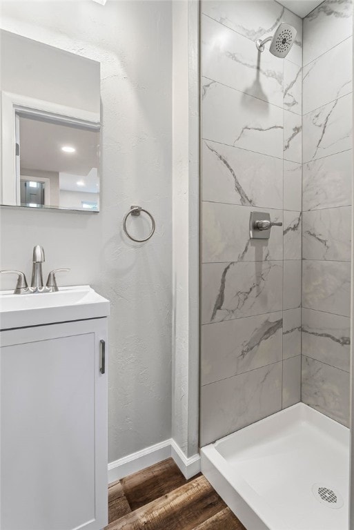 bathroom featuring a stall shower, baseboards, wood finished floors, and vanity