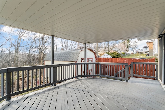 wooden terrace featuring a storage shed, fence, and an outdoor structure