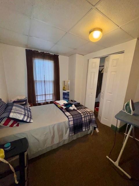 bedroom with a paneled ceiling, a closet, and carpet flooring