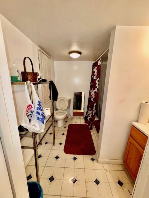 bathroom with a shower with shower curtain, vanity, toilet, and tile patterned floors