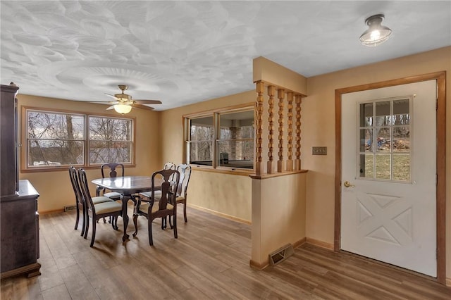 dining area with a ceiling fan, visible vents, baseboards, and wood finished floors