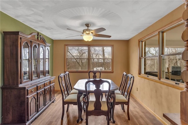 dining room with a ceiling fan, light wood-type flooring, and baseboards