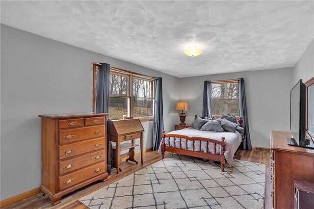 bedroom featuring light wood finished floors and baseboards