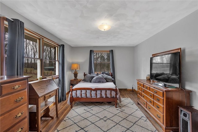 bedroom featuring light wood finished floors and baseboards