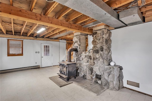 unfinished below grade area with a baseboard radiator, a wood stove, and tile patterned floors