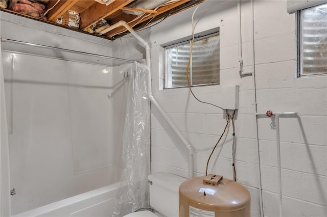 bathroom featuring shower / bath combination with curtain, toilet, and concrete block wall