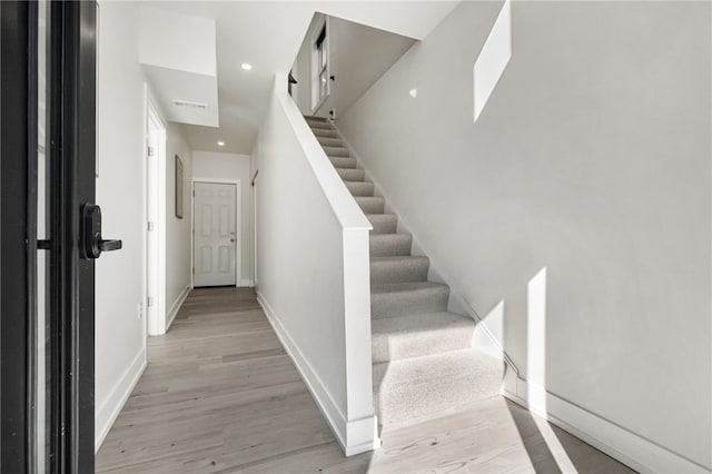 stairway featuring recessed lighting, wood finished floors, visible vents, and baseboards