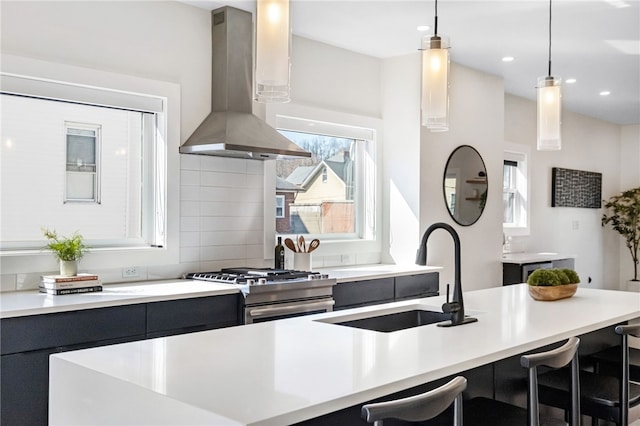 kitchen featuring island range hood, a sink, light countertops, stainless steel gas stove, and modern cabinets