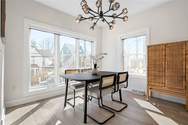 dining space with wood finished floors, visible vents, baseboards, and an inviting chandelier