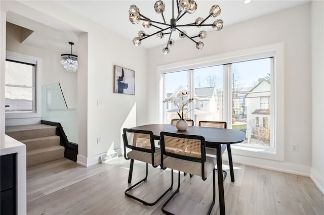 dining area featuring light wood-style floors, stairs, baseboards, and an inviting chandelier