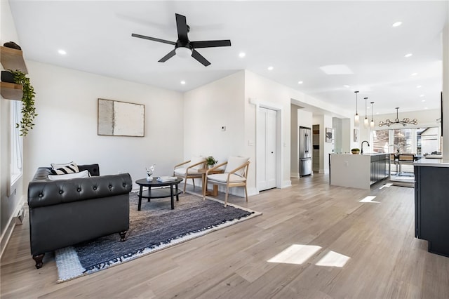 living room with light wood-style floors, recessed lighting, baseboards, and a ceiling fan