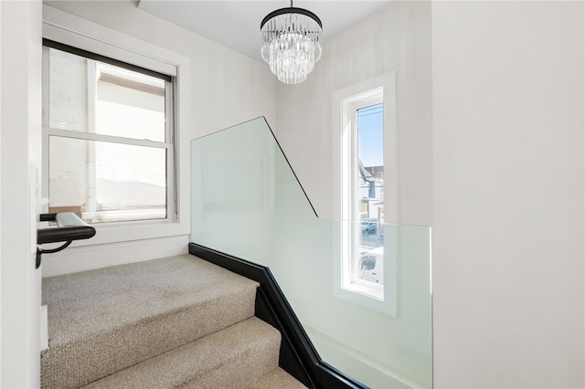 stairway featuring carpet floors and a notable chandelier