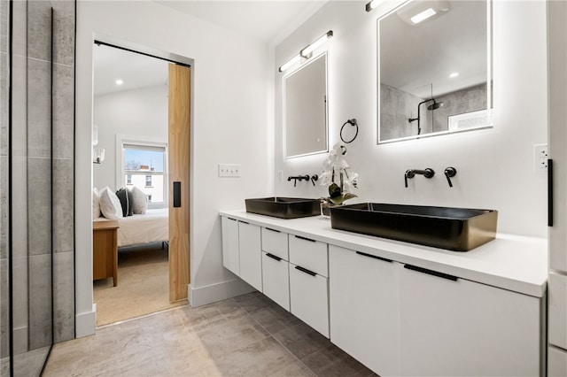 ensuite bathroom featuring double vanity, connected bathroom, a shower, and a sink