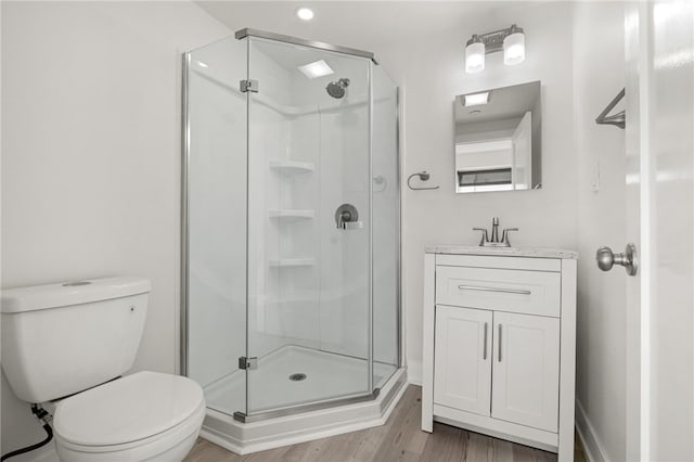 bathroom with toilet, a stall shower, wood finished floors, and vanity