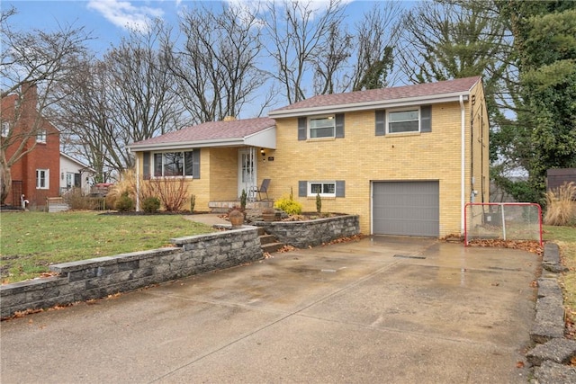 tri-level home featuring a garage, concrete driveway, brick siding, and a front lawn