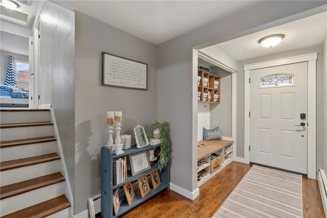 entrance foyer with a baseboard heating unit, stairs, baseboards, and wood finished floors