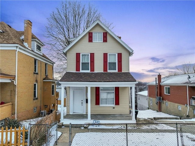 view of front of home featuring roof with shingles, a porch, and a fenced front yard