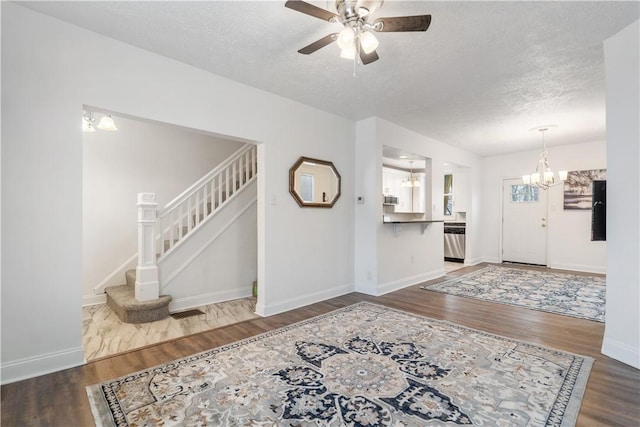 foyer featuring a textured ceiling, stairway, wood finished floors, and baseboards