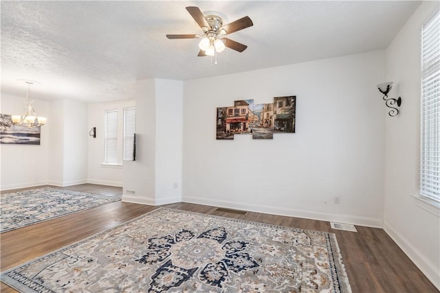 spare room with a textured ceiling, wood finished floors, visible vents, and a healthy amount of sunlight