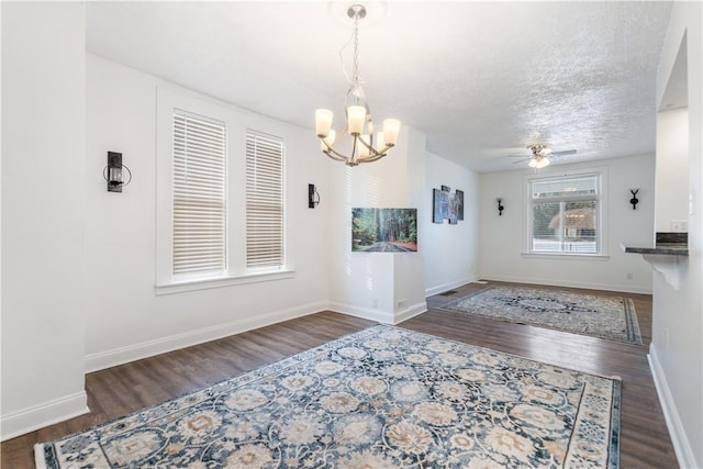 unfurnished dining area with a textured ceiling, baseboards, wood finished floors, and ceiling fan with notable chandelier