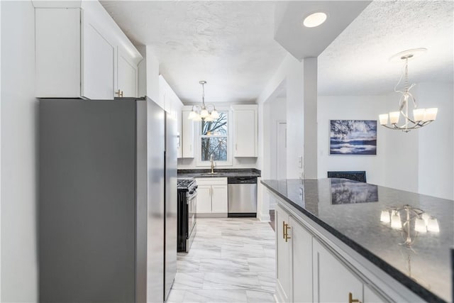 kitchen with an inviting chandelier, white cabinetry, stainless steel appliances, and a sink