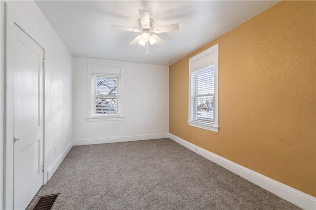 unfurnished room featuring carpet floors, visible vents, baseboards, and a ceiling fan