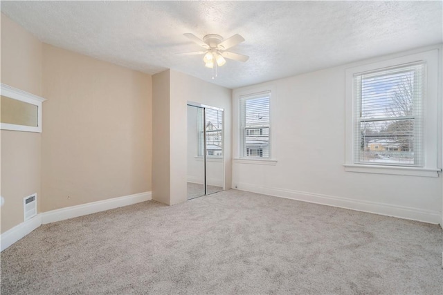 unfurnished bedroom with visible vents, carpet flooring, a textured ceiling, and baseboards