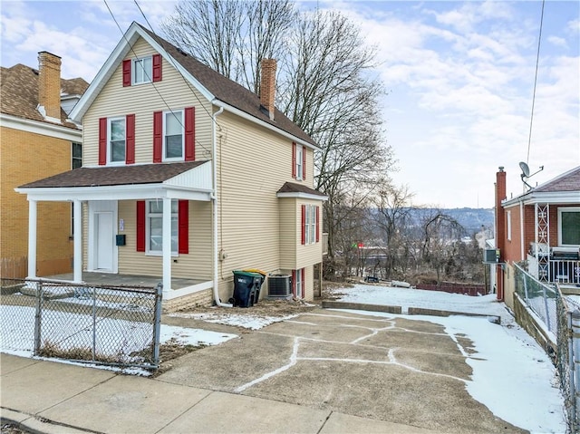 snow covered property featuring central AC, fence, a chimney, and roof with shingles