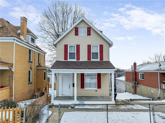 view of front facade featuring covered porch, a fenced front yard, and roof with shingles