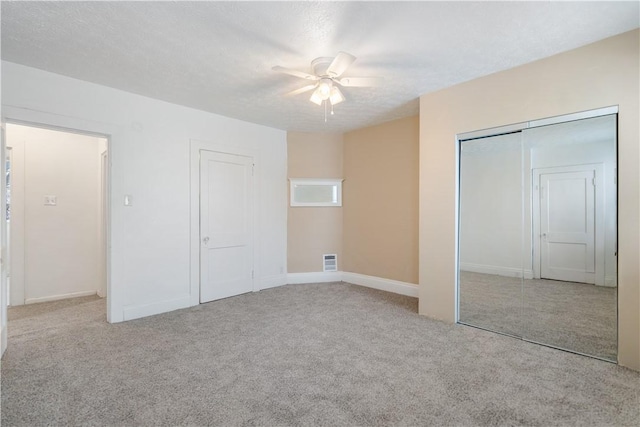 unfurnished bedroom featuring a textured ceiling, carpet floors, visible vents, baseboards, and a ceiling fan