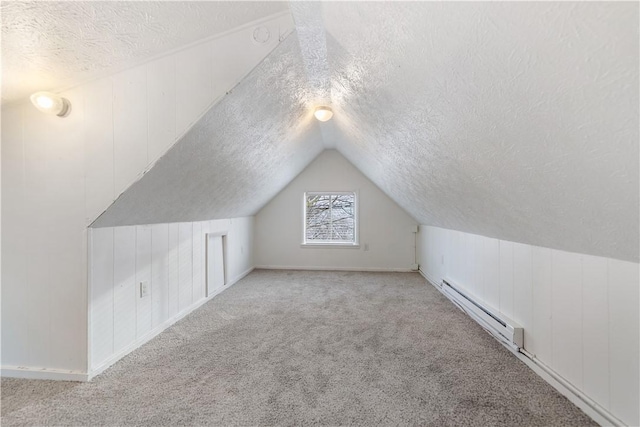 bonus room featuring a baseboard radiator, vaulted ceiling, a textured ceiling, and carpet