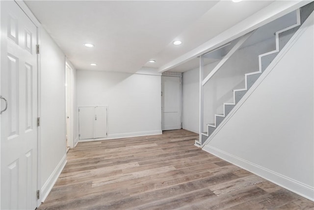 finished basement with baseboards, stairway, light wood-type flooring, and recessed lighting